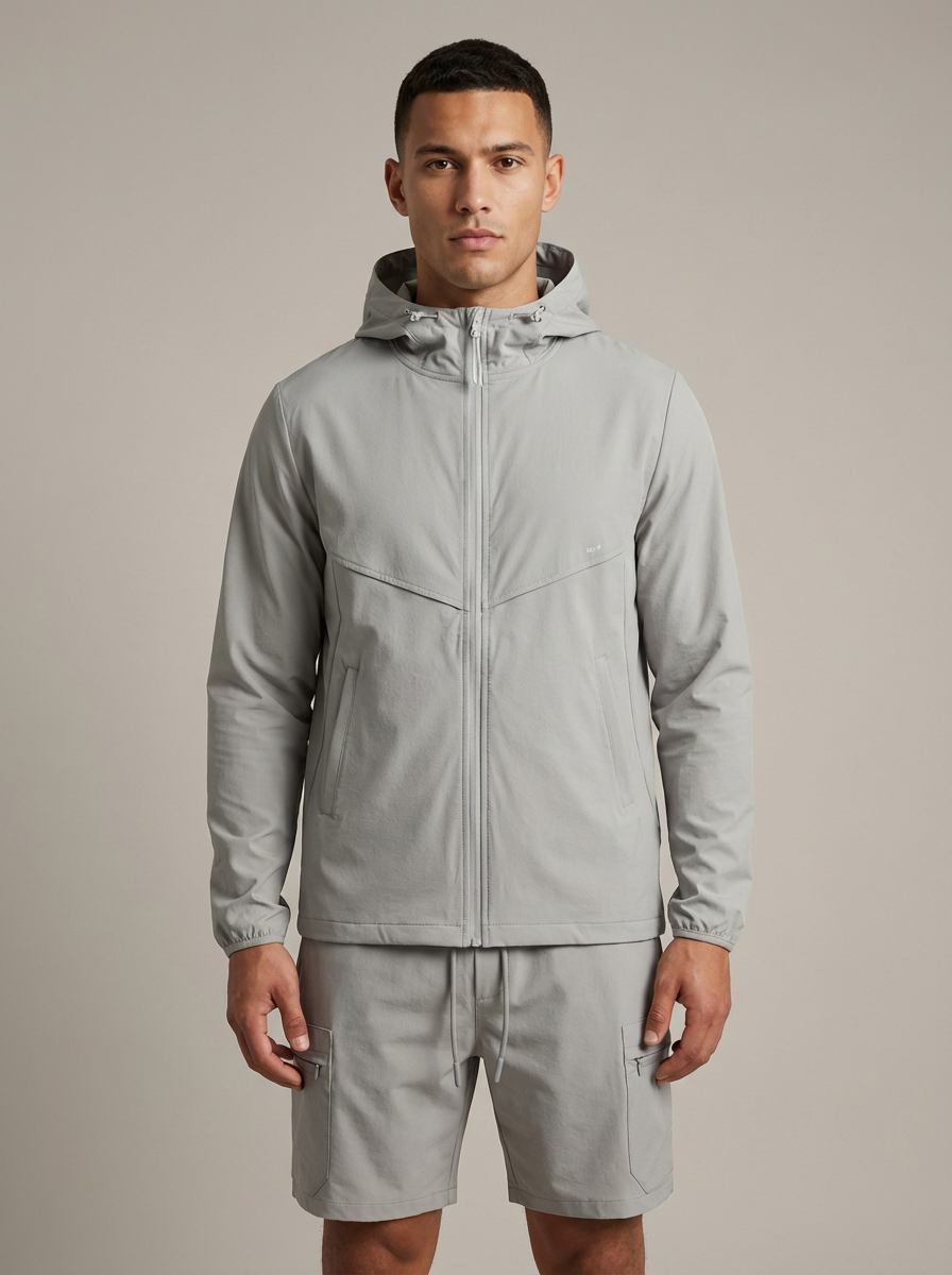 Man wearing a gray raincoat and shorts on a beige background