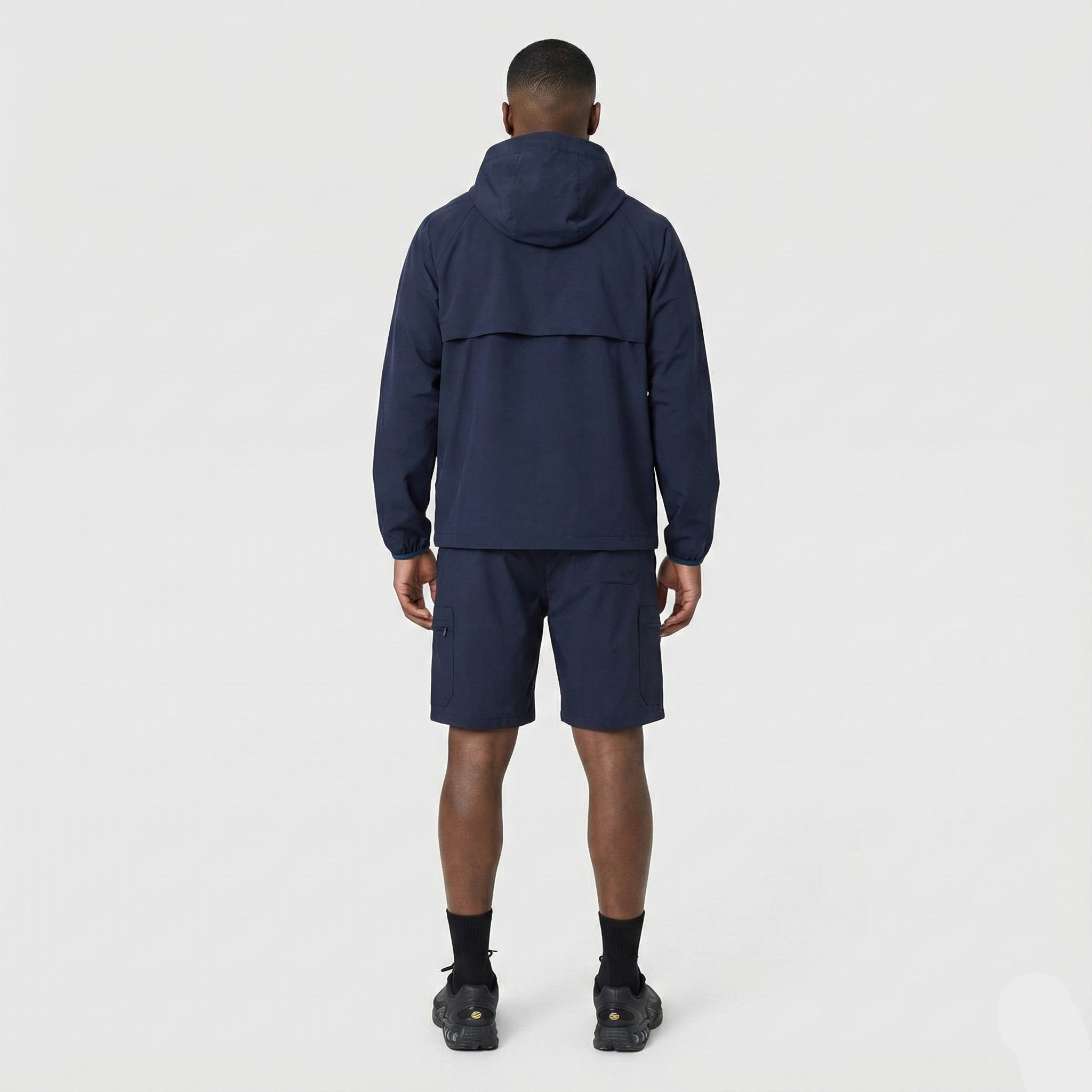 Person wearing a navy blue jacket and shorts set on a white background