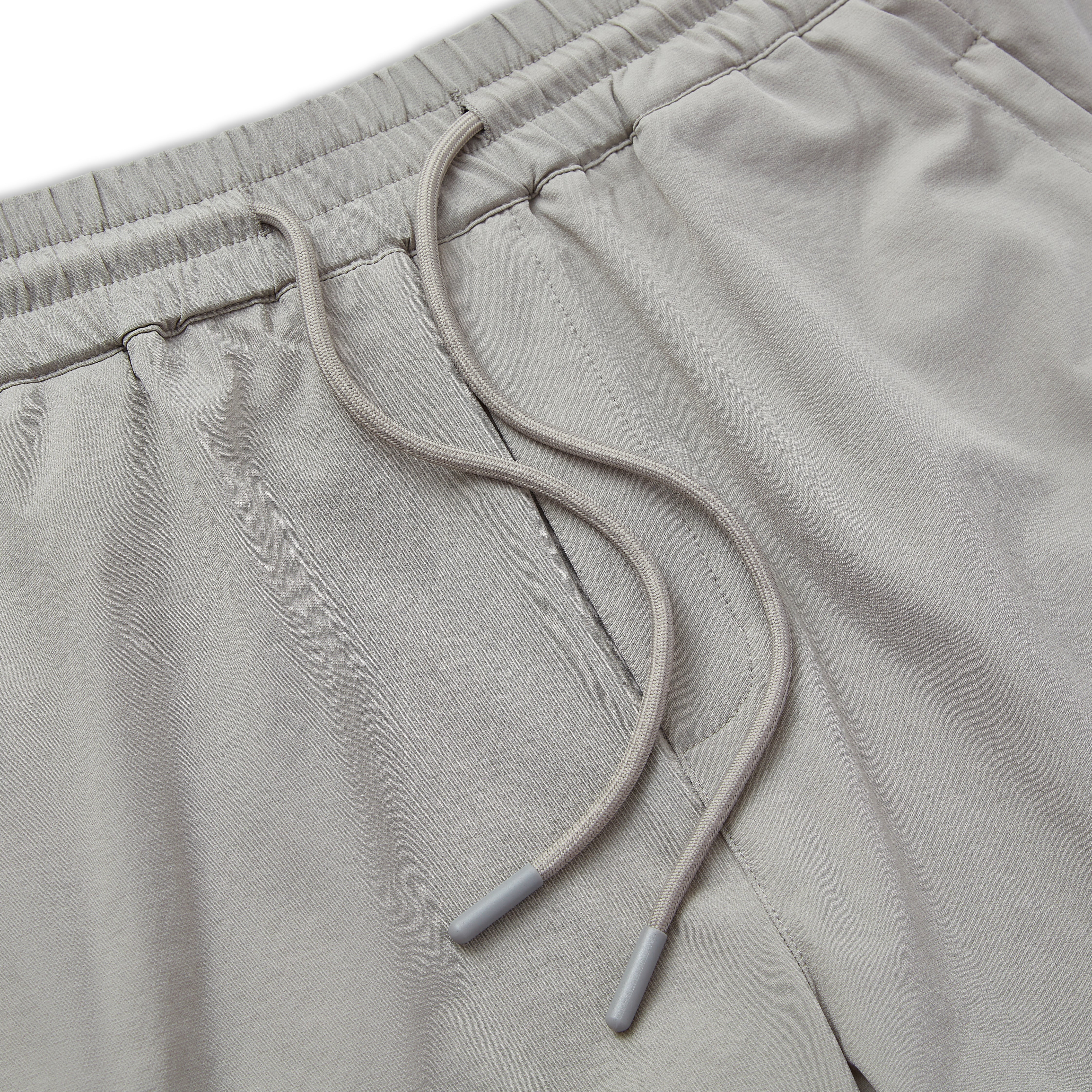 Close-up of light gray shorts with drawstring on a matching background