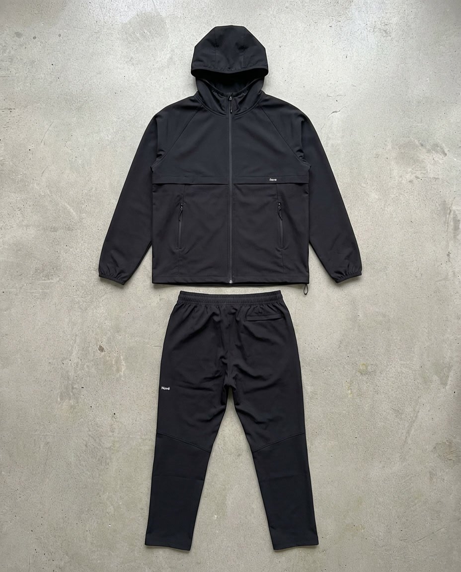 Black jacket and pants set on a gray concrete surface