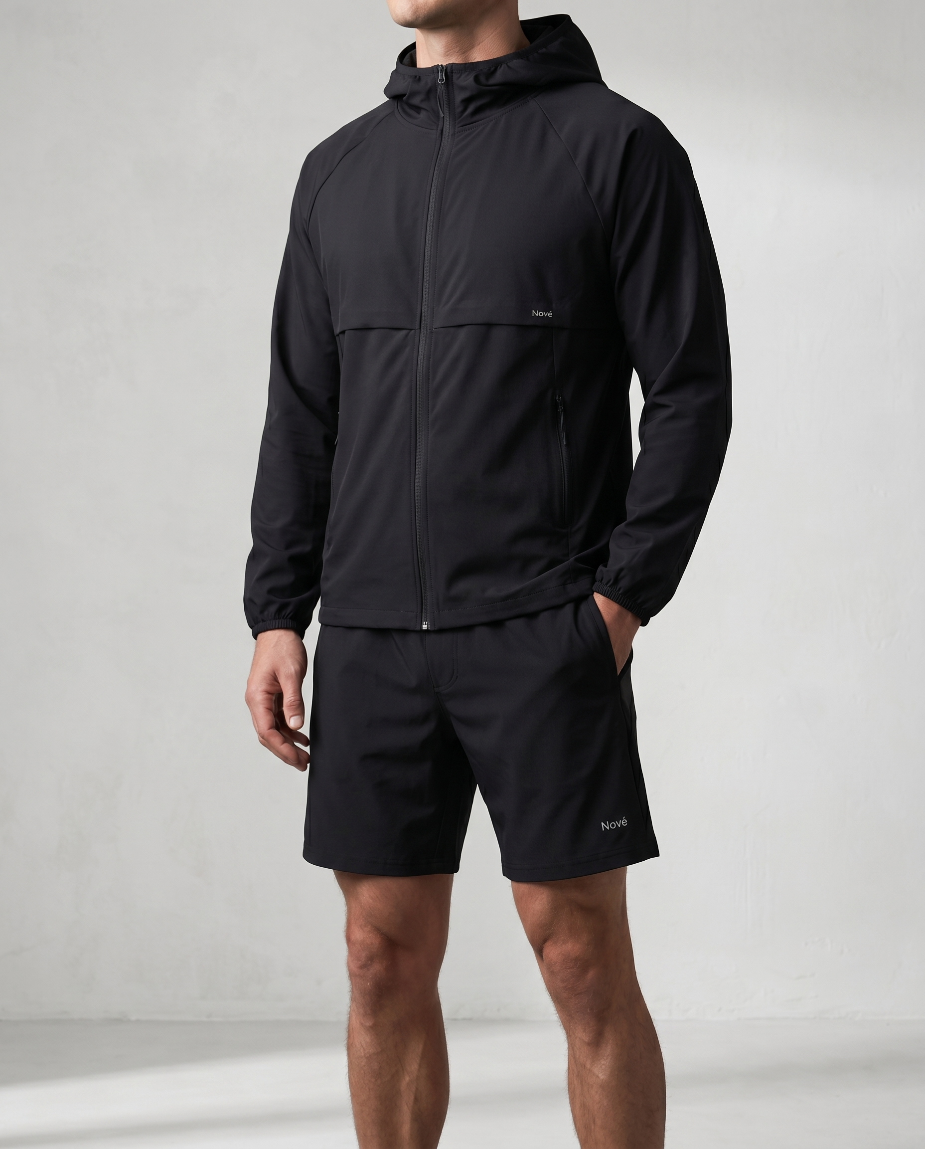 Person wearing a black jacket and shorts on a light gray background
