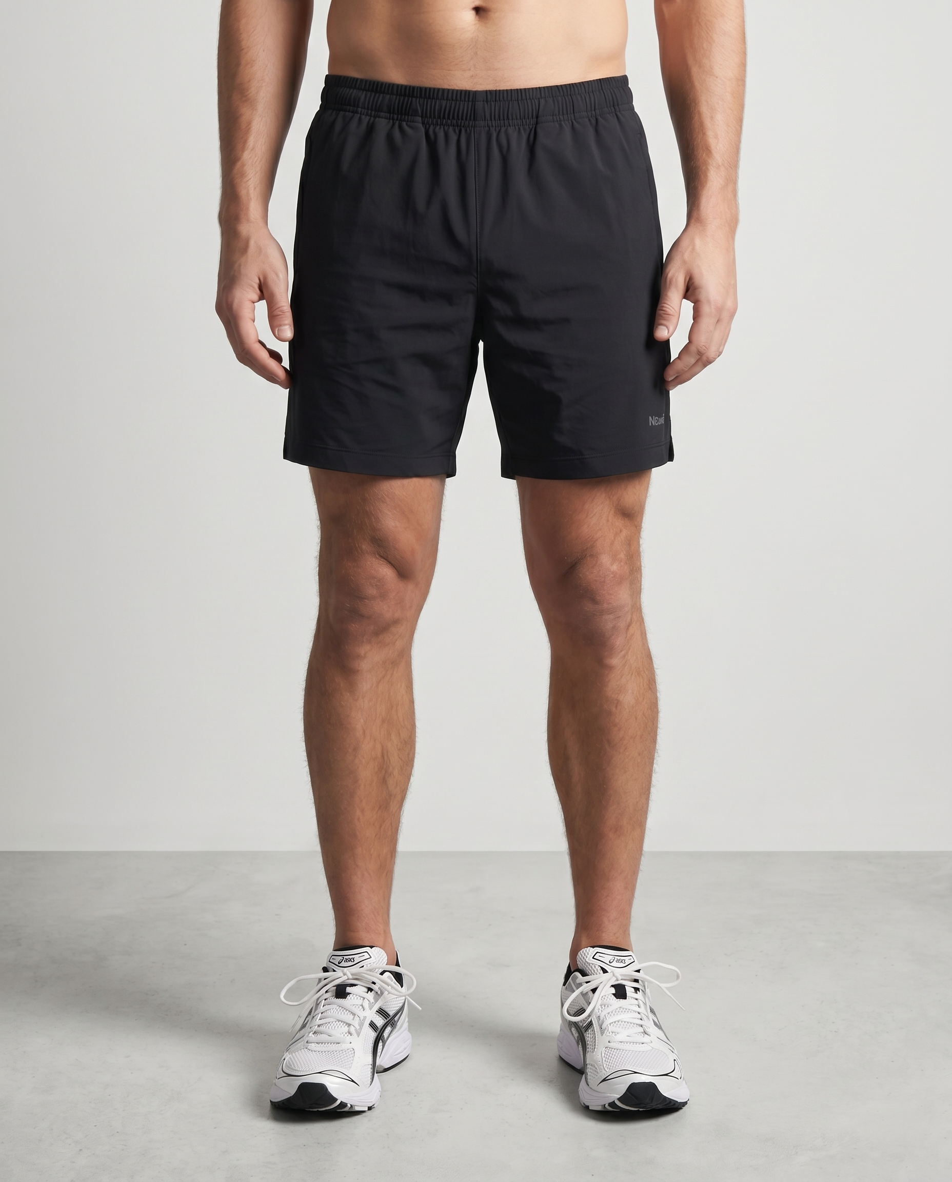 Person wearing black shorts and white sneakers on a plain background