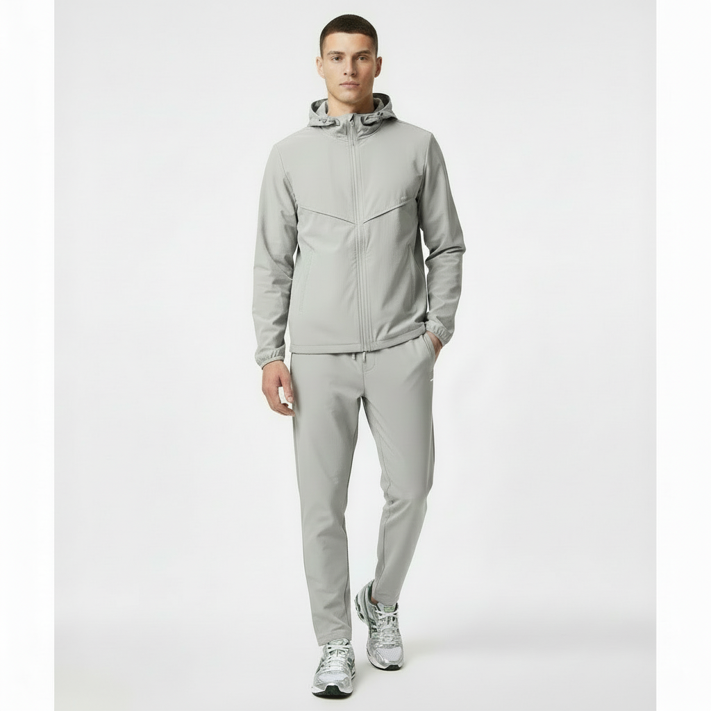 Model wearing grey windbreaker and bottoms on a white background